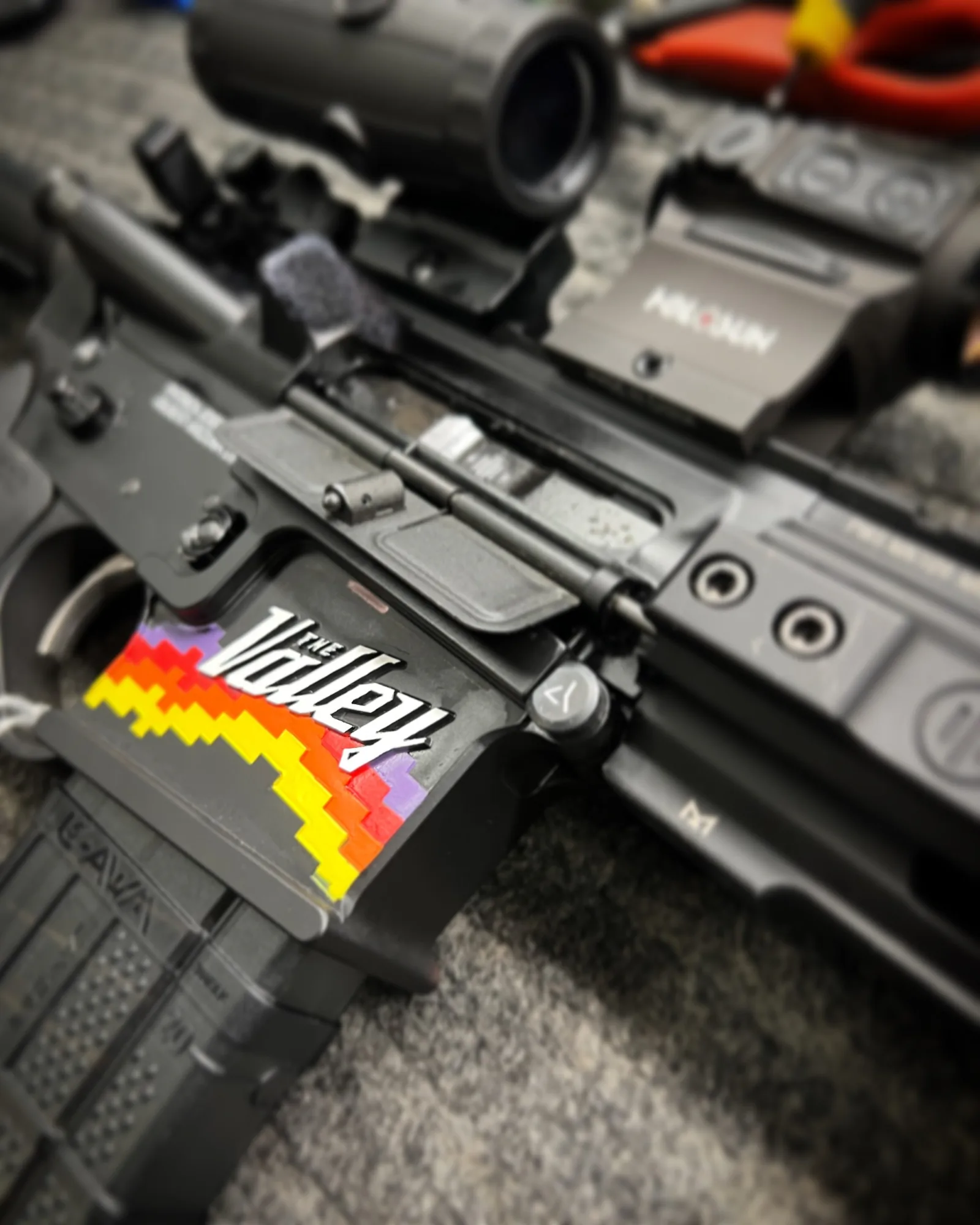 Close-up of a firearm with a colorful Valley-style graphic on its receiver.
